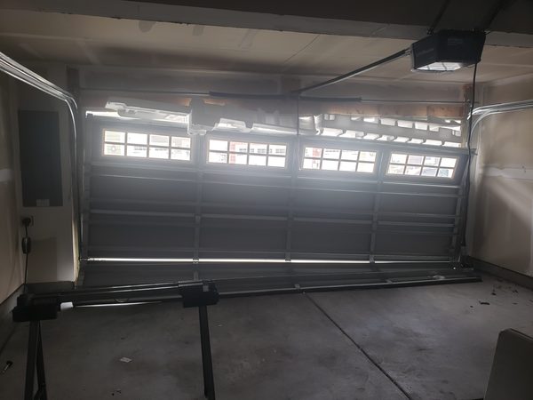 Technician measuring a garage door opening for a replacement at a Virginia Beach 23464 home, checking width, height, and headroom clearance.