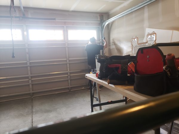 Technician installing a wind-rated insulated garage door mid-job in Hampton Roads as part of a pre-hurricane-season reinforcement.