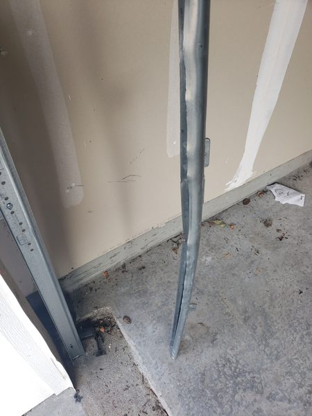 Technician working at the lower garage door track where the safety sensors mount on a Virginia Beach home in 23454
