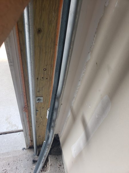 Technician repairing a bent vertical garage door track section on a coastal Hampton Roads home