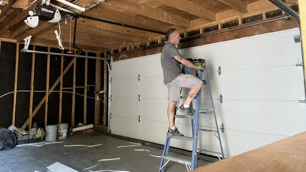 Seaside Garage Door technician on a ladder servicing a residential garage door in Hampton Roads